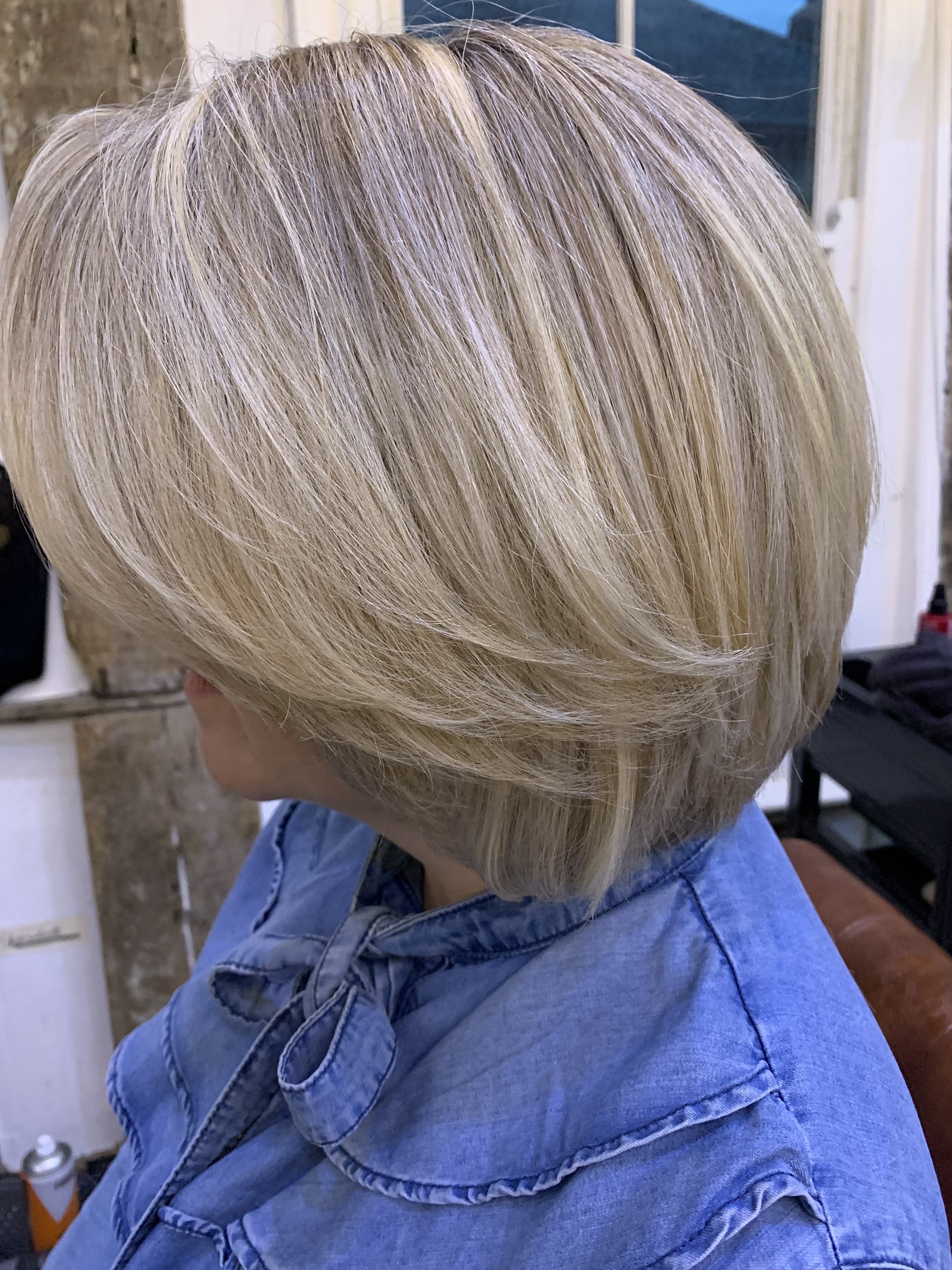 A soft blonde bob with layered highlights, seen from the side in the salon